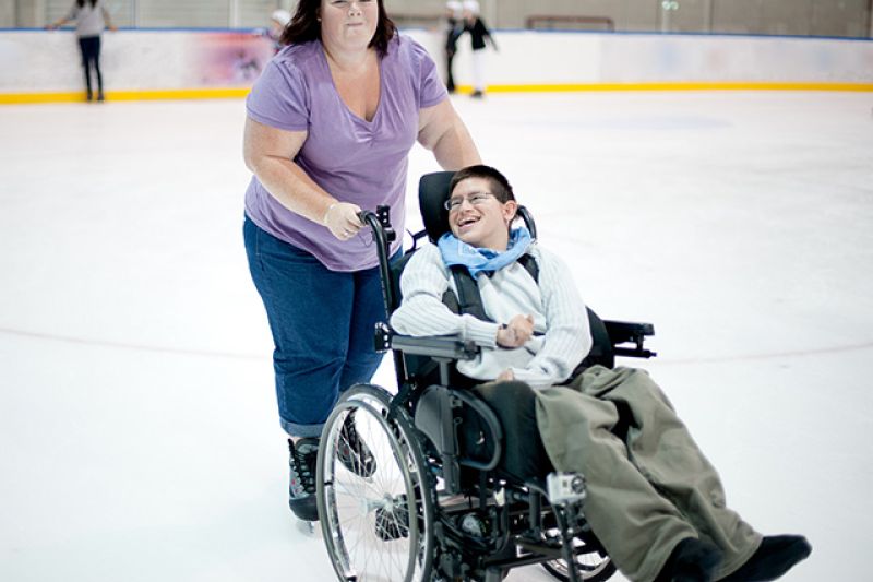 woman pushing a child in a wheelchair in an ice rink