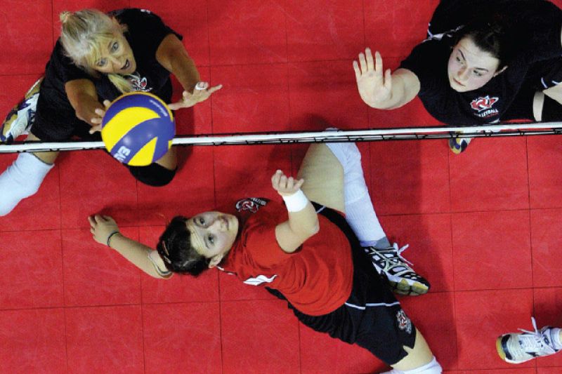 top view of sitting volleyball players lobbing the ball over the net