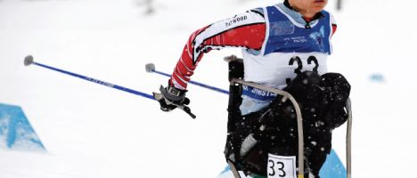 disabled male competitor wearing a race number on nordic sit ski competing