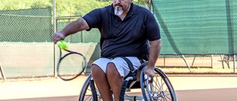 man in a wheelchair playing tennis on a court